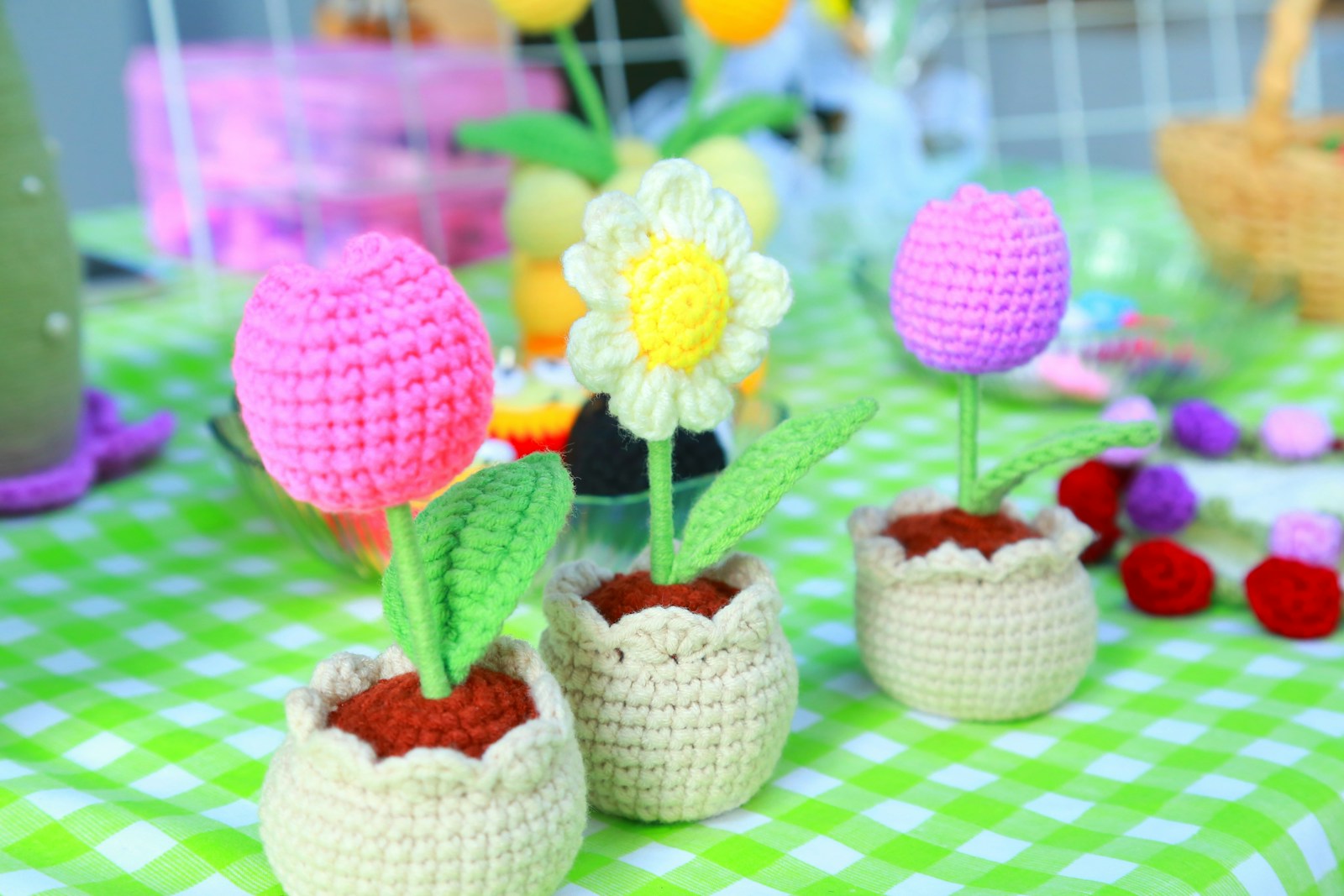 Crocheted tulips and daisy in pots on table.